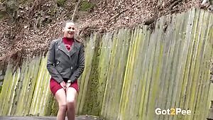 Cute brunette rushing to spray a stream of piss against a wall
