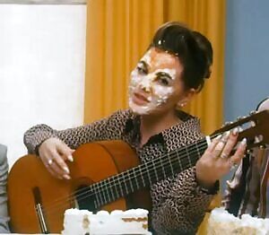 Playing the guitar with cake on her face